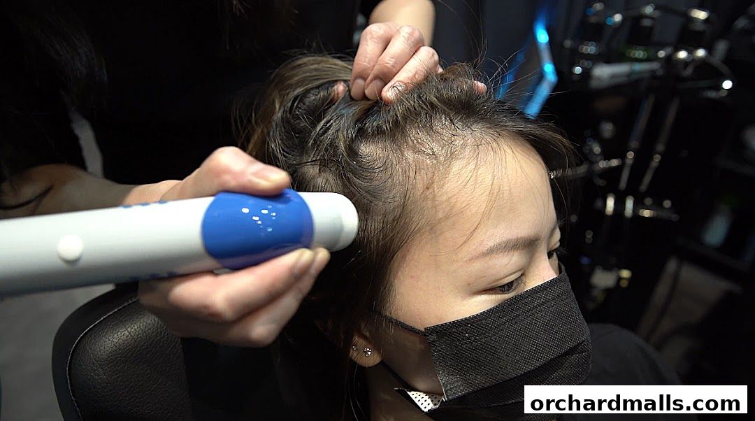 A person receives a scalp treatment with a specialized device at Papilla By Kim Lim.