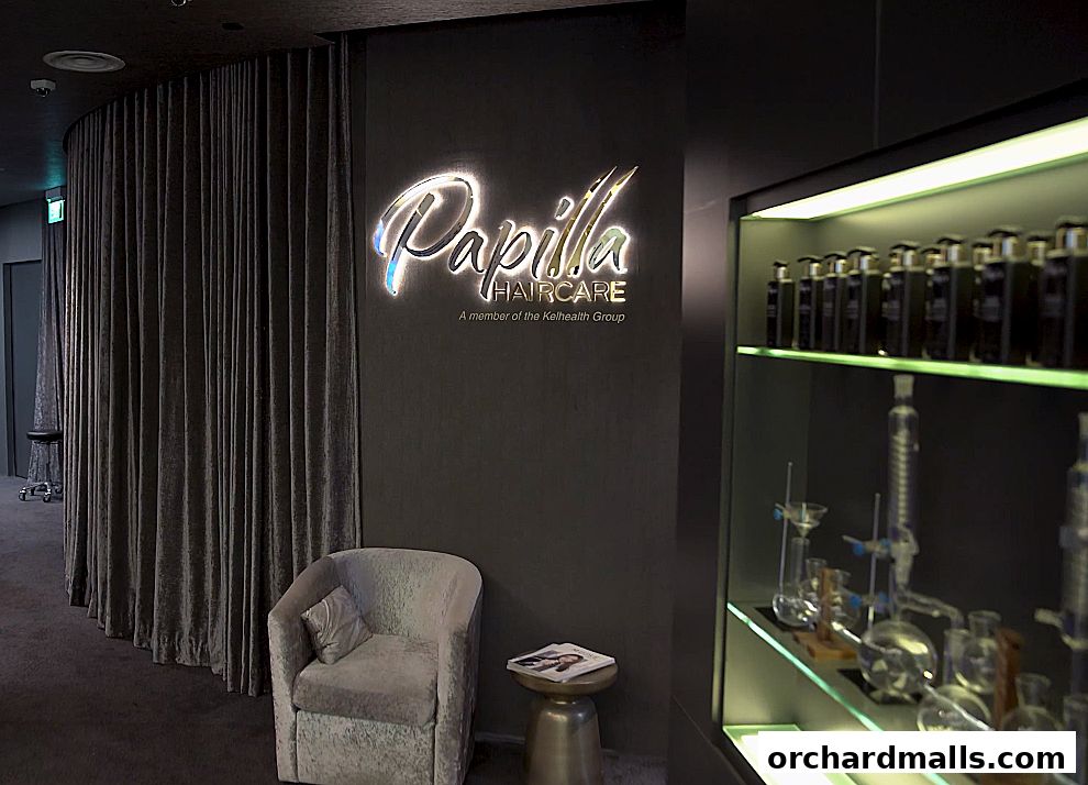 Interior of Papilla Haircare with a neon sign, armchair, and display shelves.