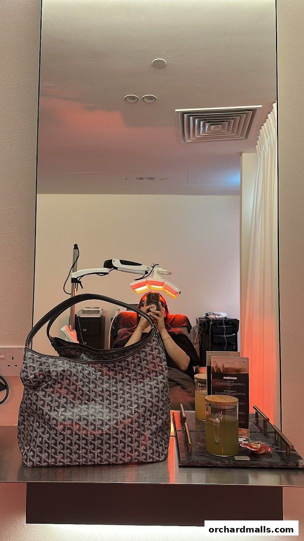 A person takes a selfie in a mirror at Papilla By Kim Lim, with a handbag in the foreground.