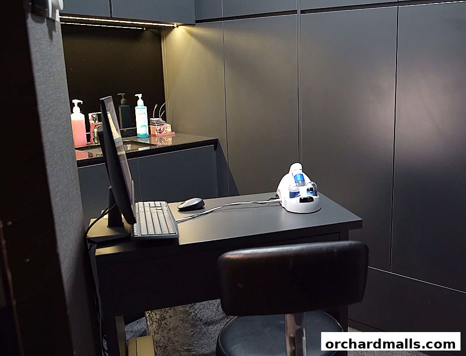 A modern reception desk with a computer, keyboard, mouse, and a beauty device.