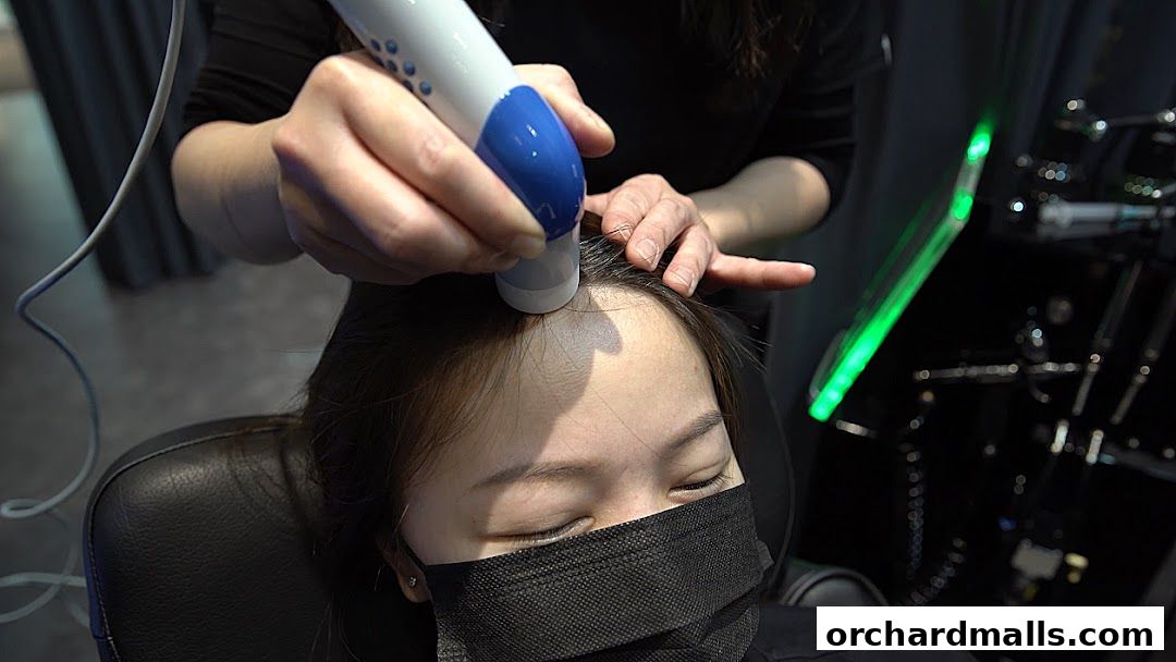 A person receives a scalp treatment with a handheld device at Papilla By Kim Lim.