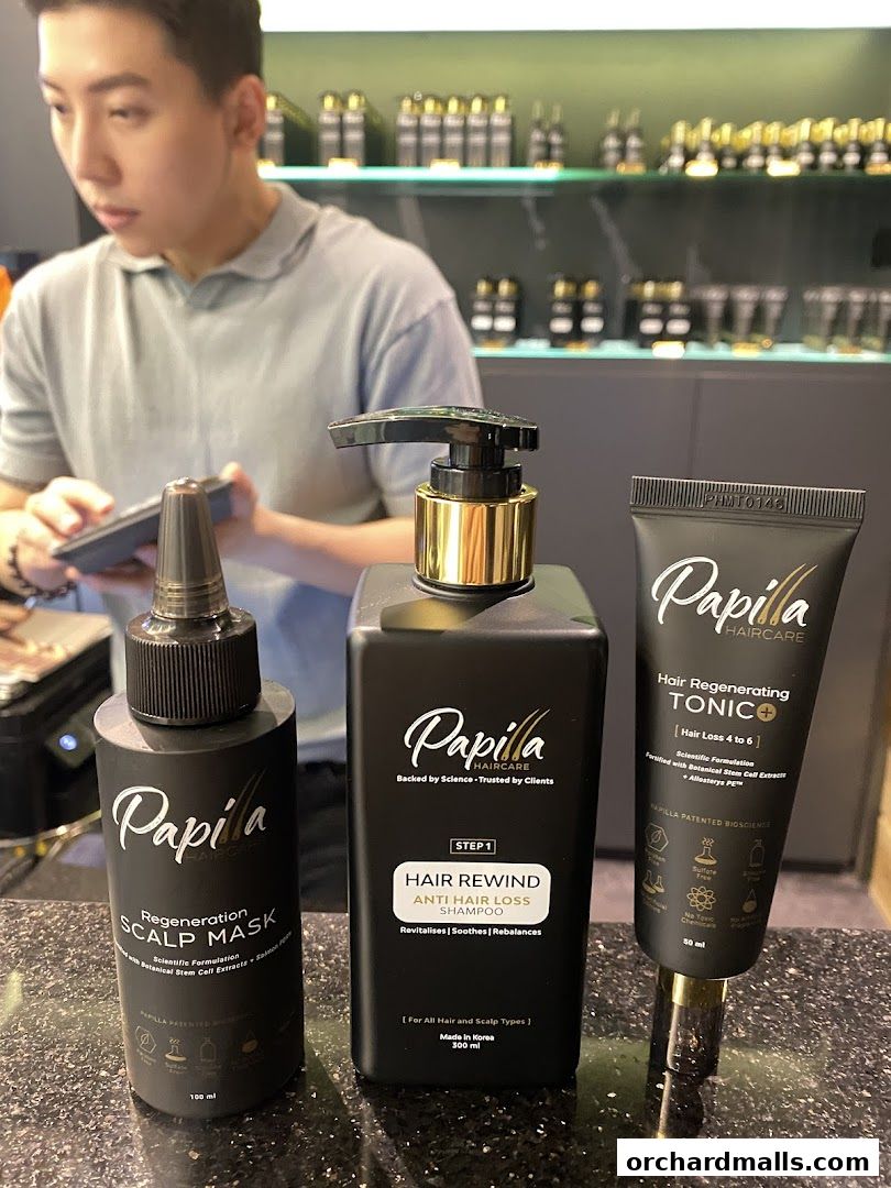 Papilla Haircare products displayed with a staff member in the background.