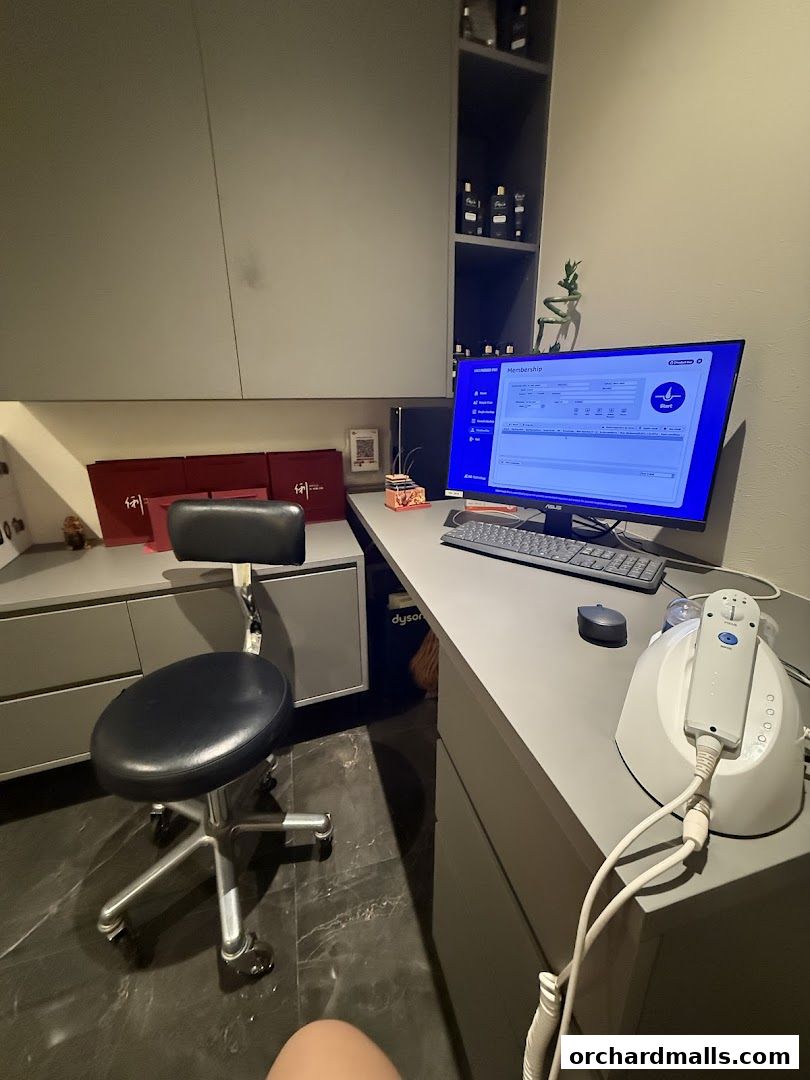 A modern reception desk with a computer displaying membership information and a treatment device.