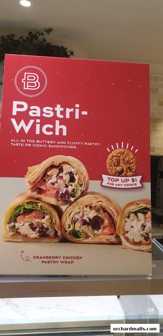 A sign advertising Paris Baguette's Cranberry Chicken Pastry Wrap with a cookie offer.