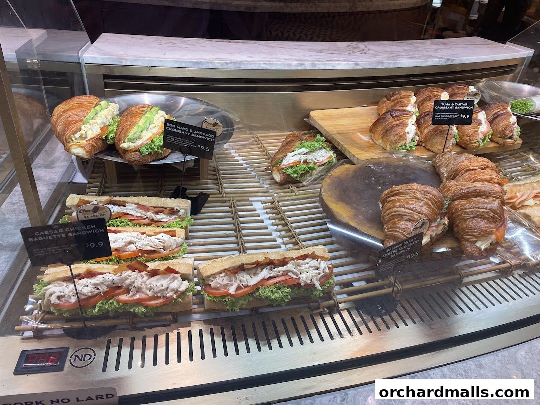A display case filled with various sandwiches and croissants from Paris Baguette.