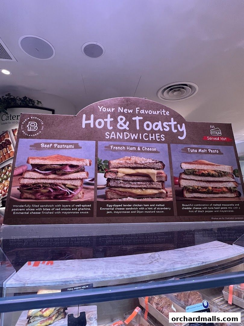 A display board showcasing three hot and toasty sandwiches from Paris Baguette.