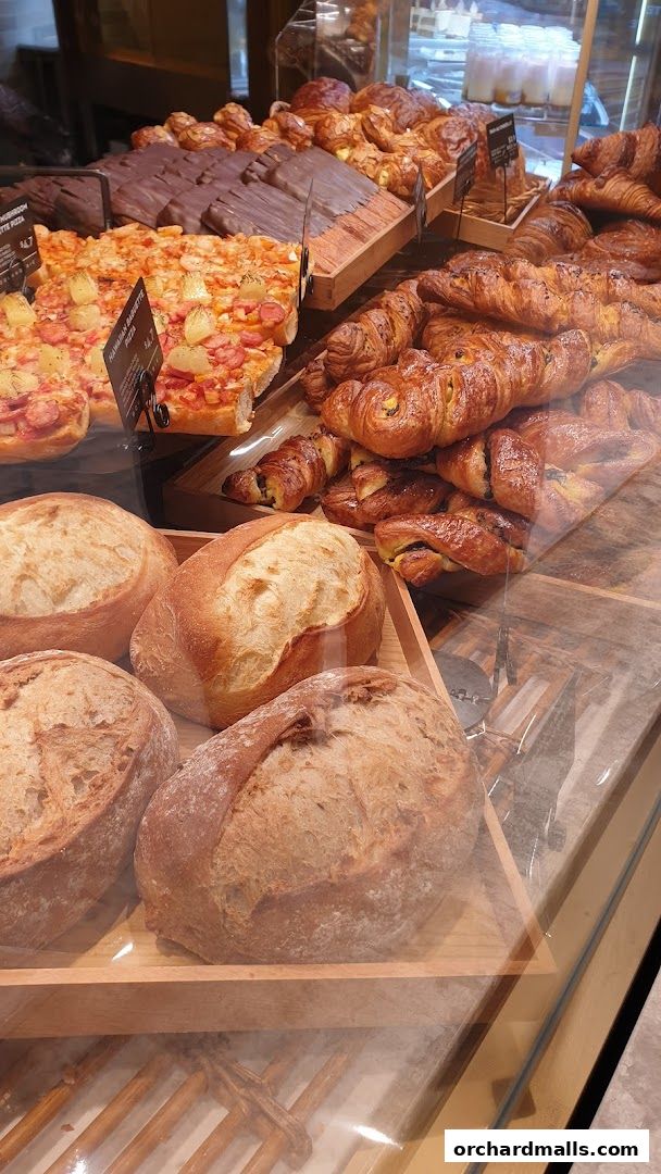 A display of freshly baked breads, pastries, and pizzas at Paris Baguette.