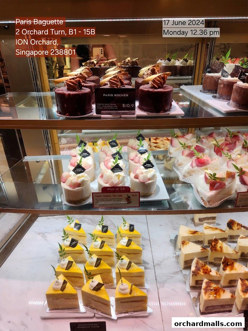 A display case filled with various cakes and pastries at Paris Baguette.