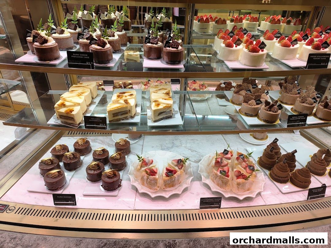 A display case filled with various beautifully decorated cakes and pastries from Paris Baguette.