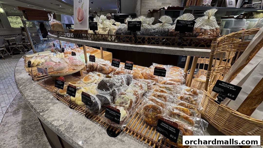 A display of freshly baked breads and pastries at Paris Baguette, with various items individually packaged.