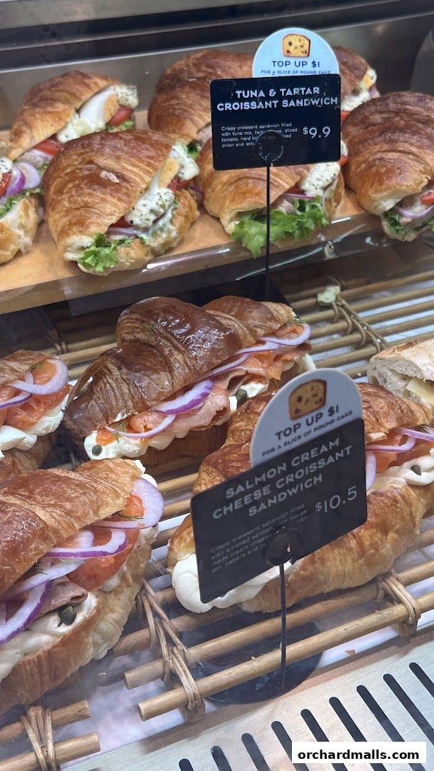 A display of freshly made croissant sandwiches with various fillings and prices.