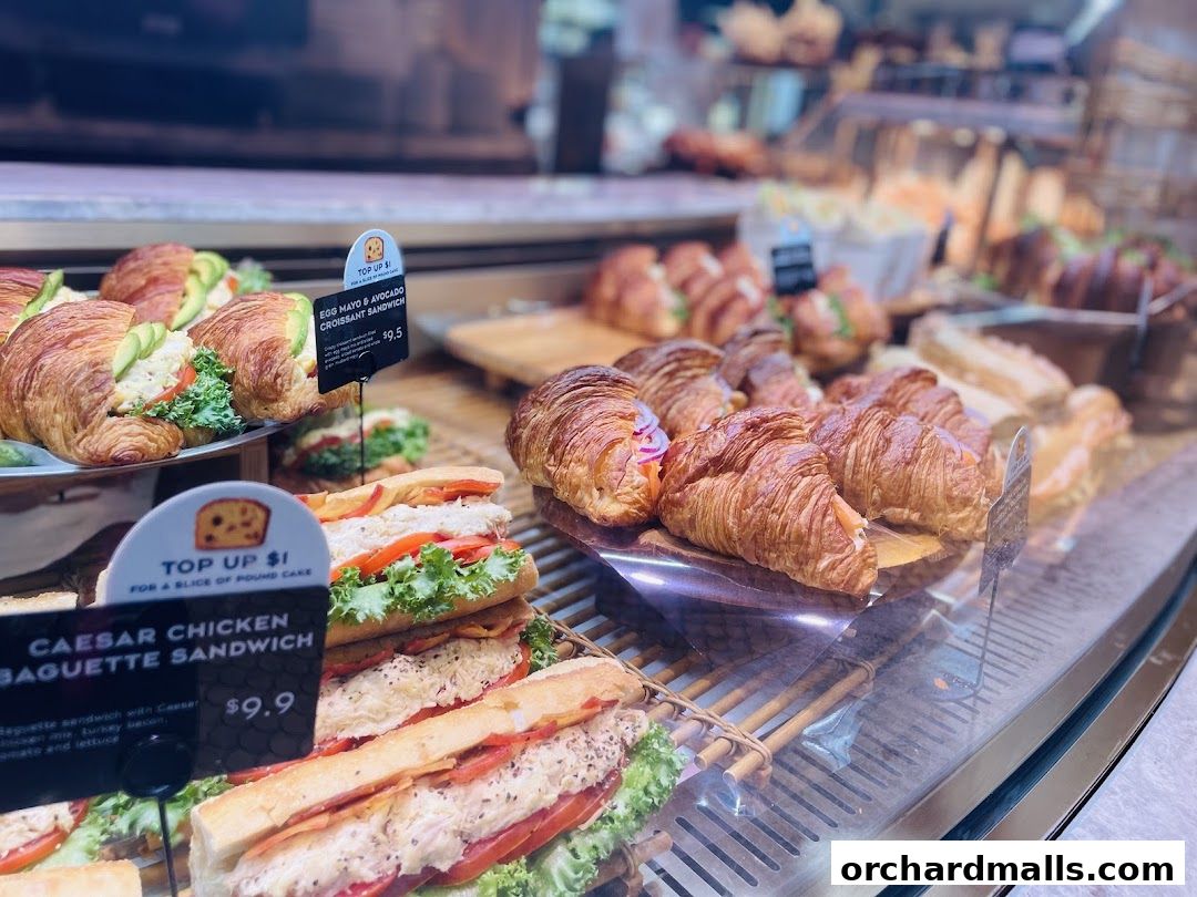 A display case filled with fresh croissants and sandwiches at Paris Baguette.