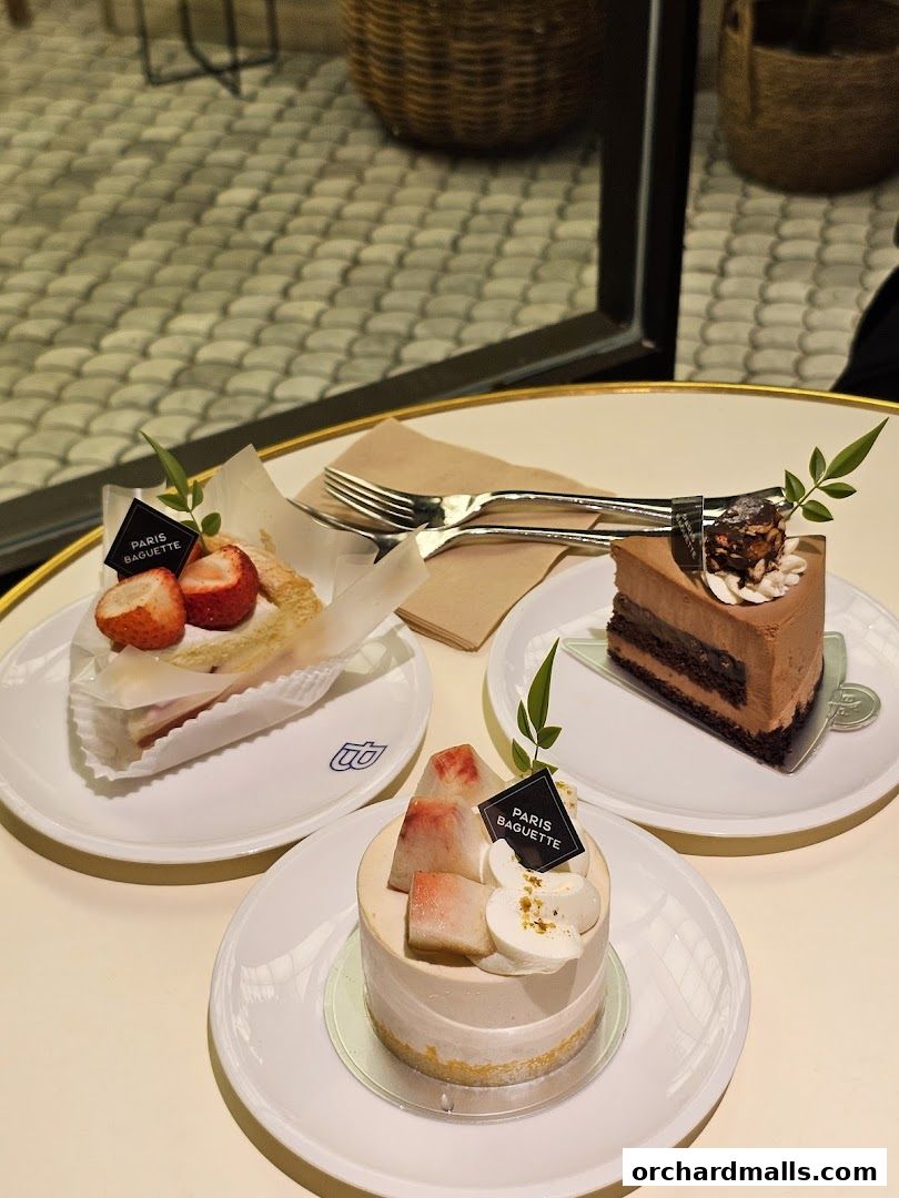 Three delicious cakes from Paris Baguette, including a strawberry tart, a chocolate cake, and a peach cake.