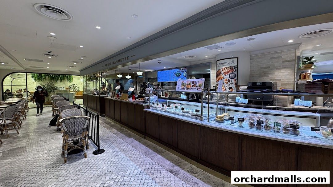 Interior view of Paris Baguette cafe with seating, counter, and display cases filled with food.