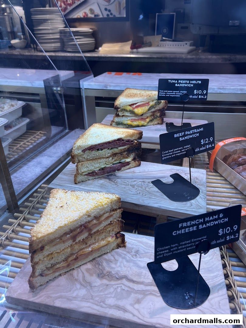 A display of gourmet sandwiches, including tuna pesto, beef pastrami, and French ham and cheese.