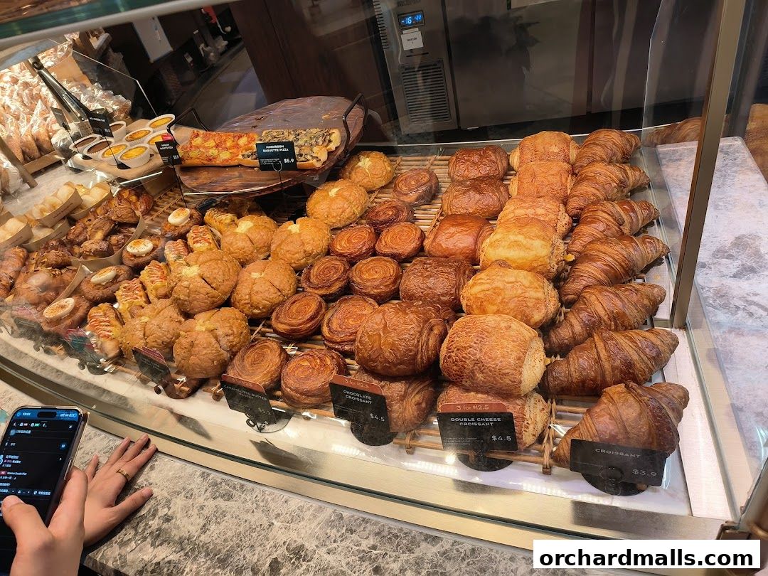 A display case filled with a variety of freshly baked pastries and breads at Paris Baguette.