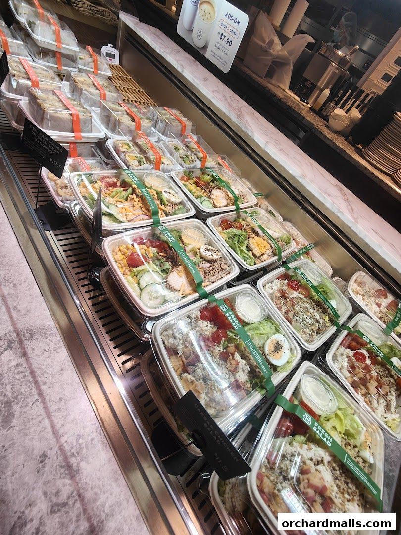 A display case filled with pre-packaged sandwiches and fresh salads from Paris Baguette.