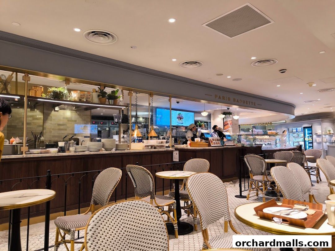 Interior view of Paris Baguette cafe with seating, counter, and display cases.