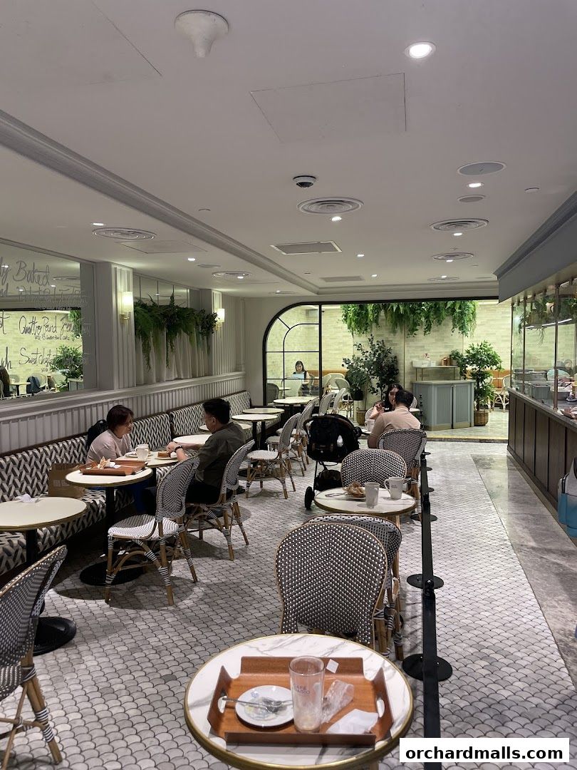 Interior view of a Paris Baguette cafe with customers seated at tables.