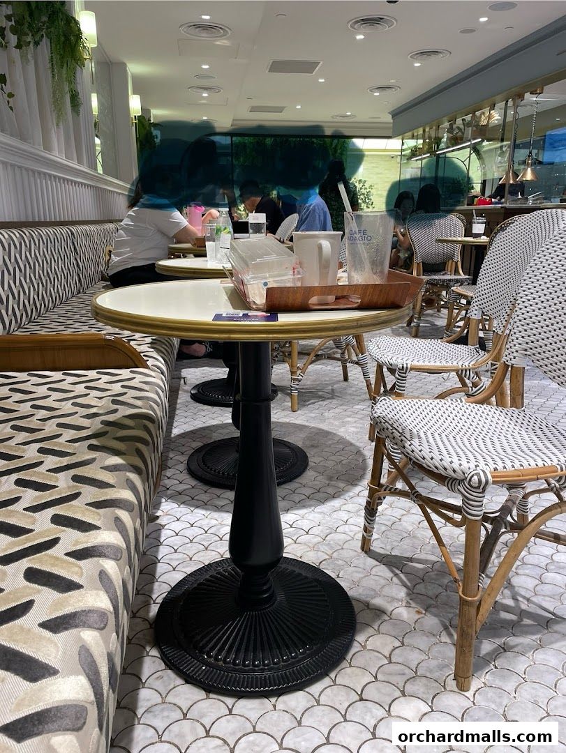 Interior shot of Paris Baguette cafe with patrons seated at tables and chairs.
