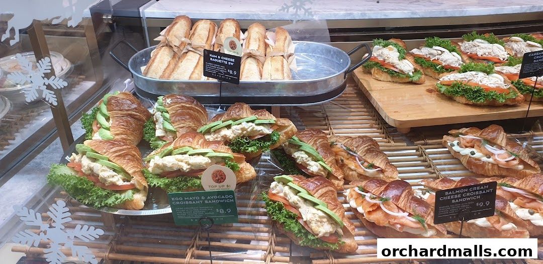 A display of freshly made croissants and baguettes filled with various ingredients.