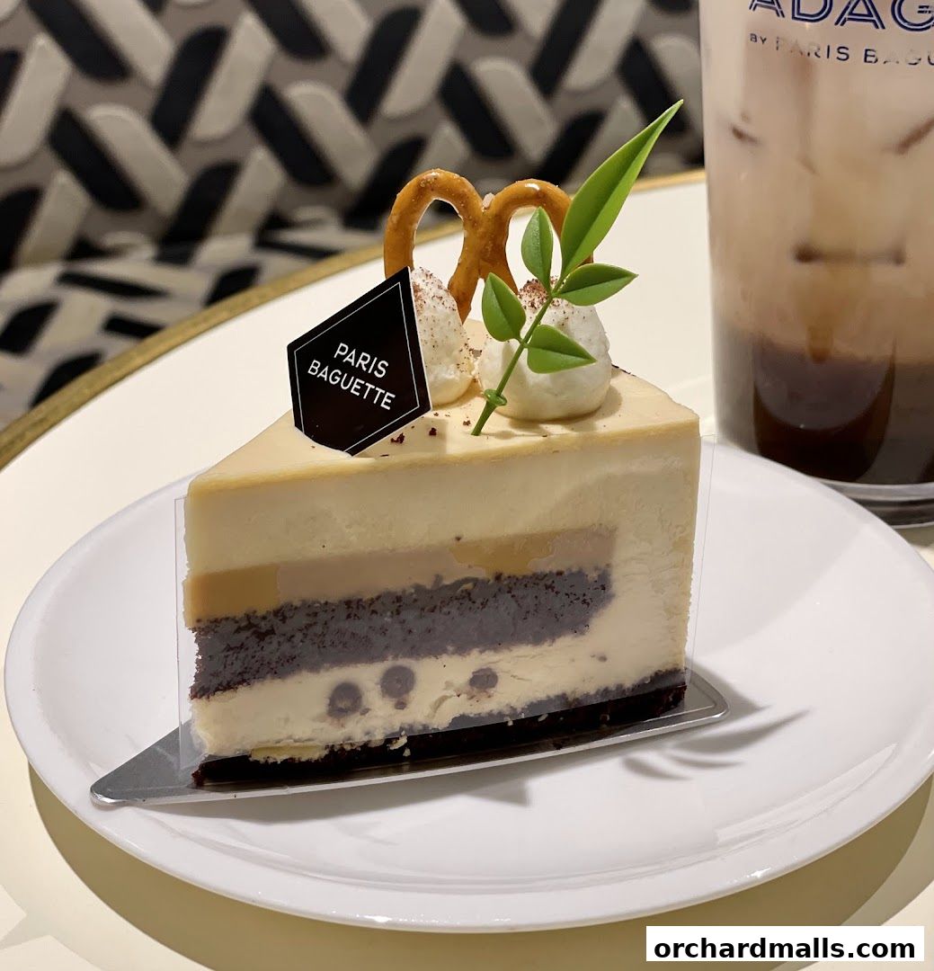 A slice of layered cake with pretzels and a drink from Paris Baguette.