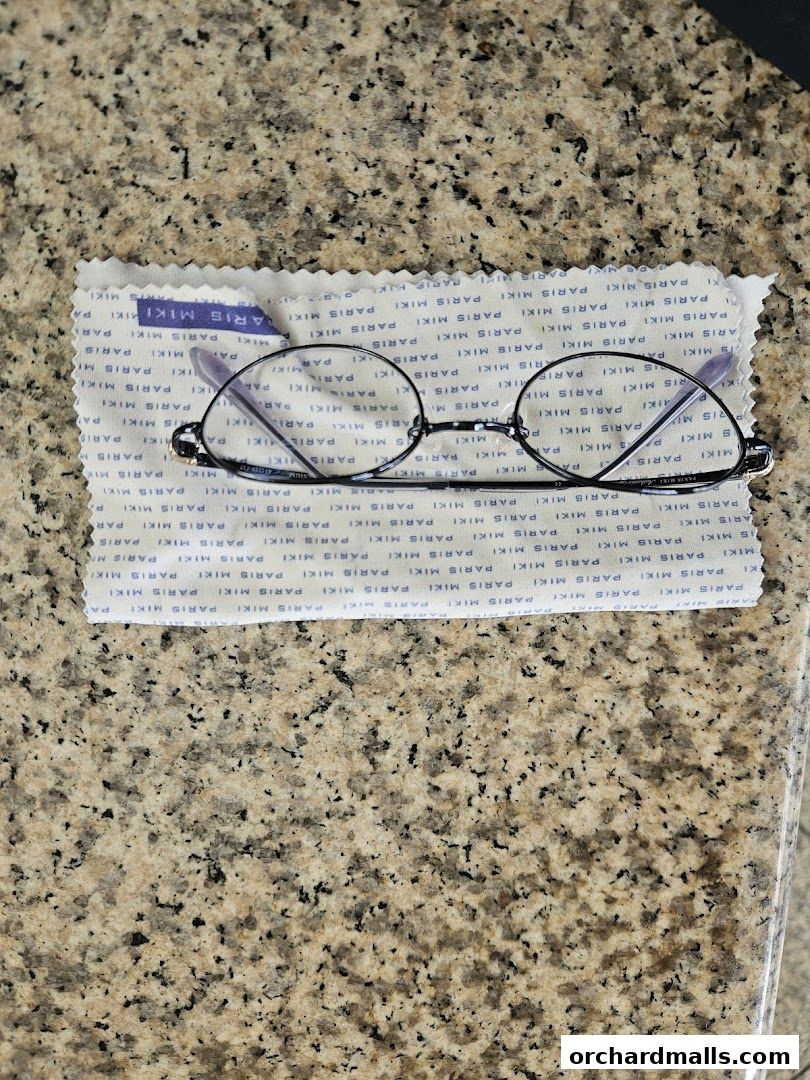 A pair of stylish eyeglasses resting on a branded cleaning cloth.