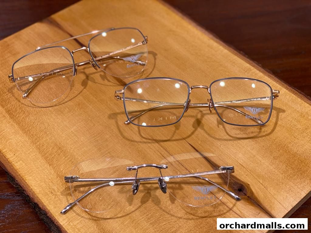 Three pairs of stylish eyeglasses displayed on a wooden surface.
