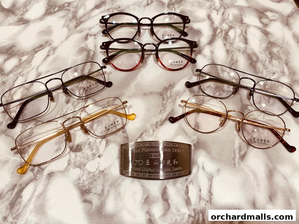 A collection of stylish eyeglasses and a metal plaque with shop details.
