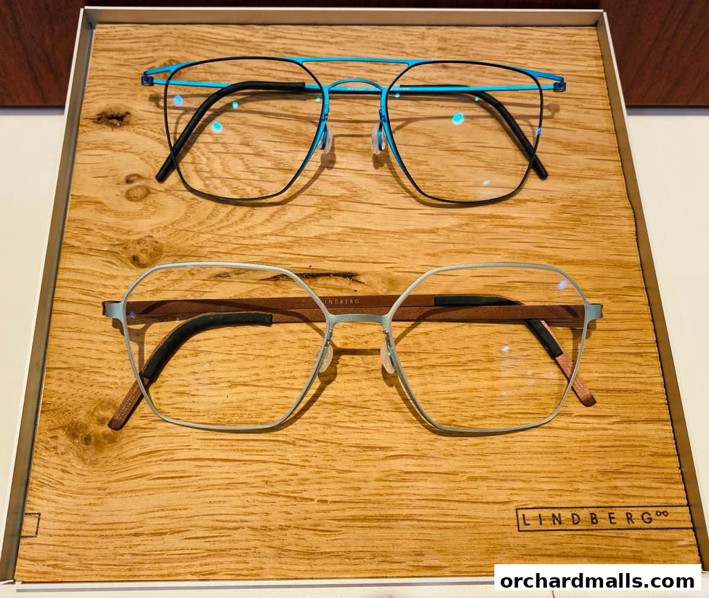 Two pairs of stylish Lindberg eyeglasses displayed on a wooden surface.