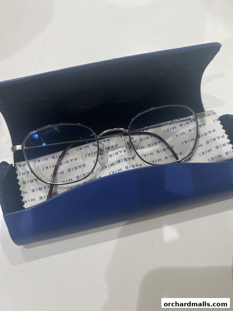 A pair of silver-rimmed glasses in a blue case with a cleaning cloth.