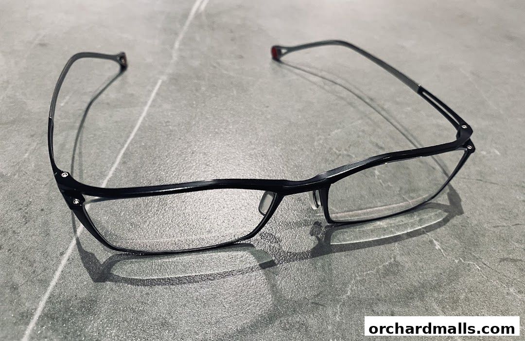 A pair of sleek, black-rimmed eyeglasses with clear lenses rests on a textured gray surface.