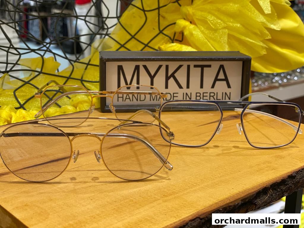 Stylish MYKITA eyeglasses displayed on a wooden surface with decorative elements.