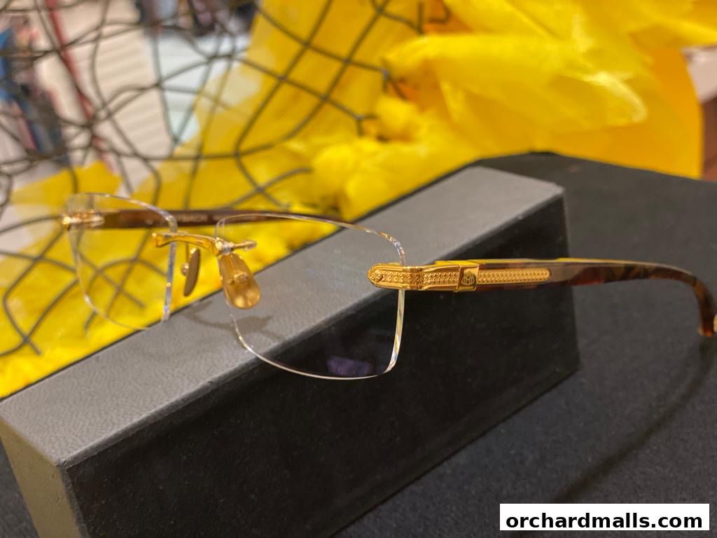 Close-up of elegant gold-rimmed eyeglasses with tortoise shell arms on a display box.