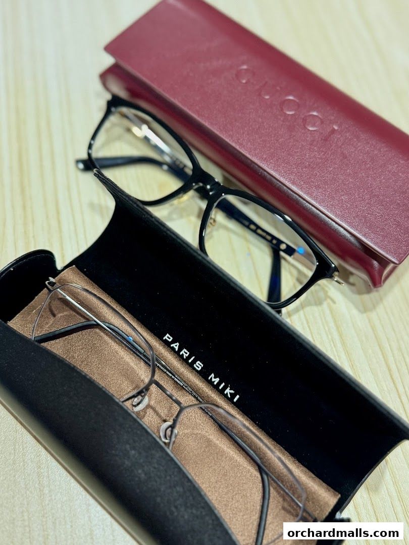 A pair of eyeglasses in a Paris Miki case next to a Gucci case.