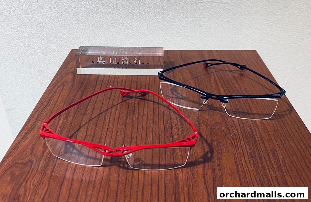 Two pairs of stylish eyeglasses, one red and one black, displayed on a wooden surface.