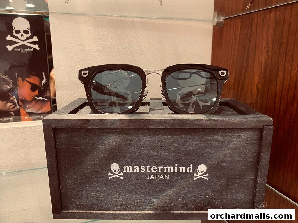 Stylish black sunglasses with skull motif displayed in a wooden box.