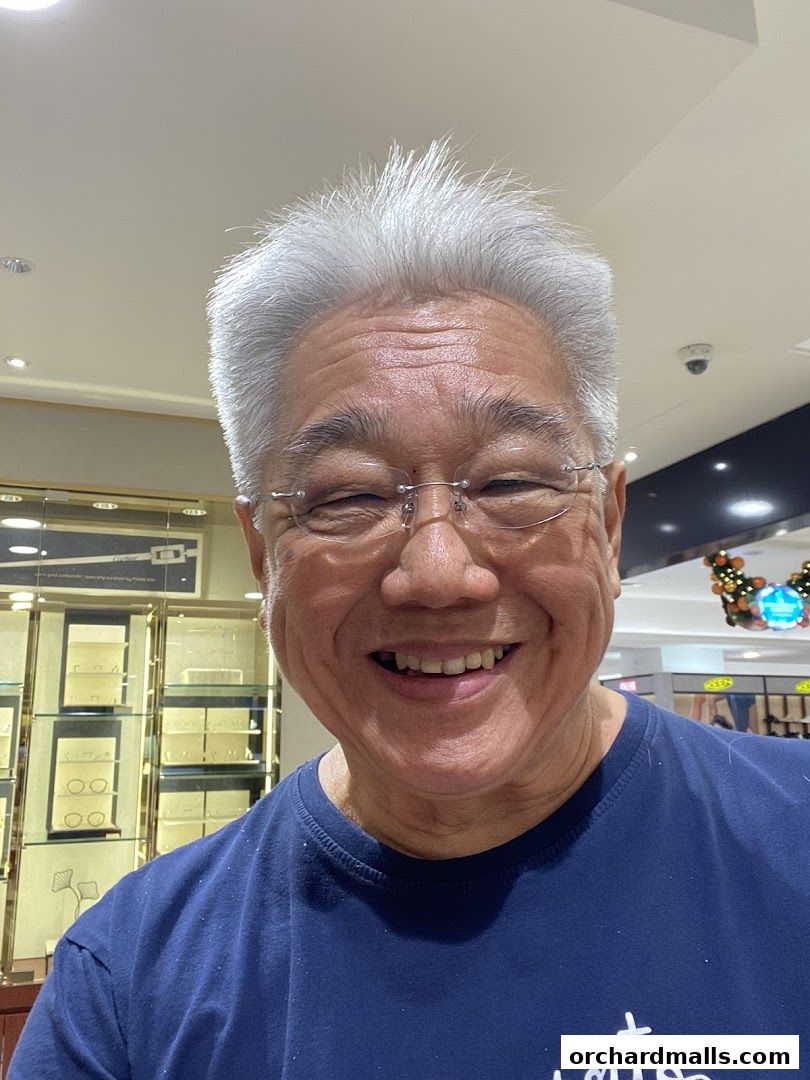 A smiling man with glasses and grey hair in a dark blue t-shirt.