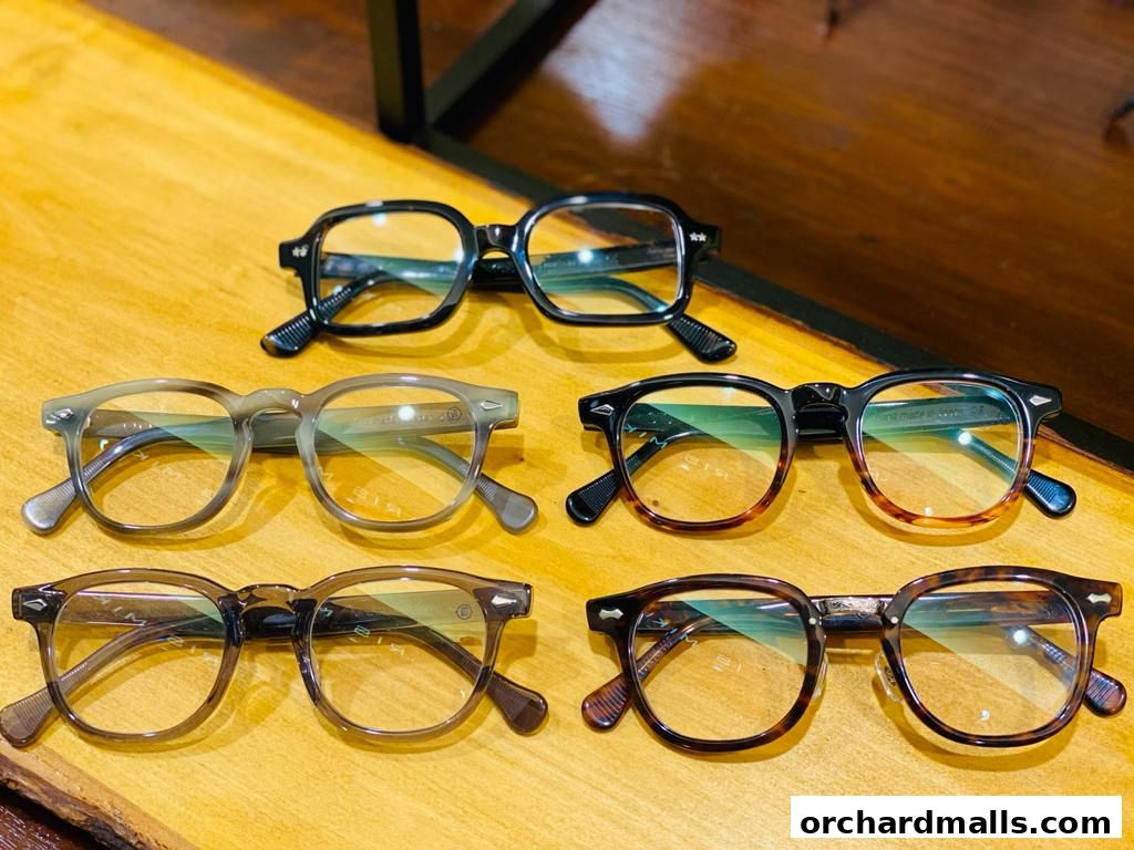A collection of stylish eyeglasses with various frame designs and colors displayed on a wooden surface.