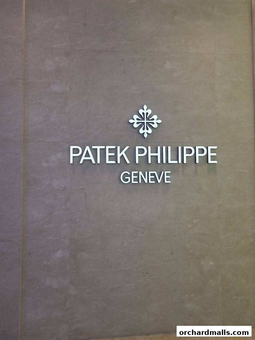 The Patek Philippe logo and name are displayed on a marble-tiled wall.