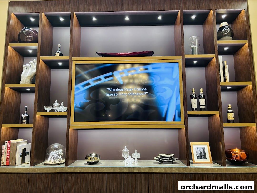 A display shelf with Patek Philippe books, decorative items, and a screen.