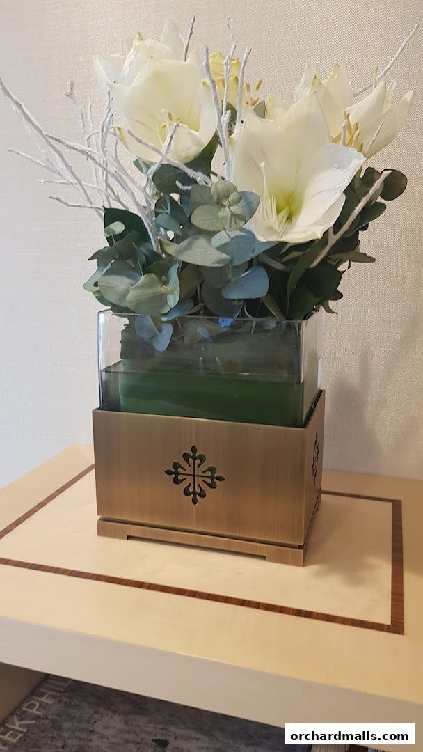 A decorative floral arrangement with white flowers and greenery in a glass vase.