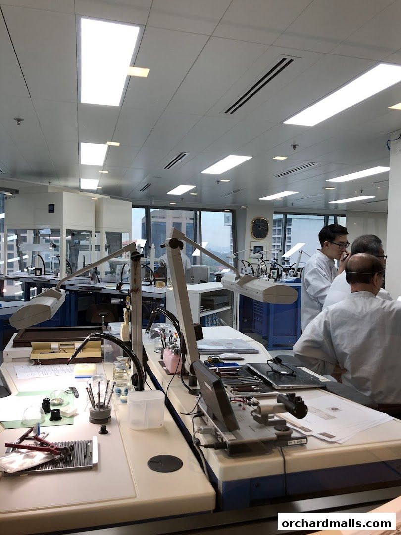 Watchmakers working at precision workstations in a Patek Philippe service center.