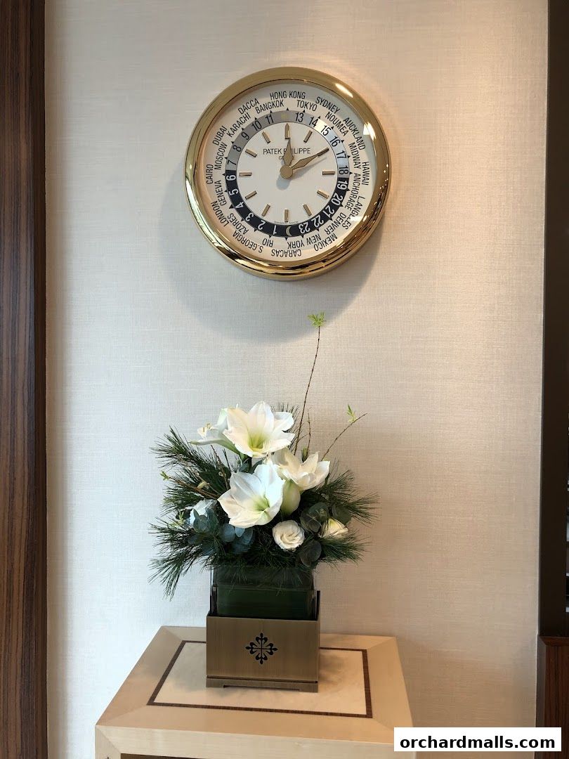 A Patek Philippe world clock and floral arrangement in a luxurious setting.