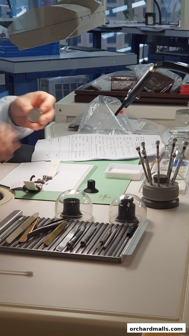 A watchmaker's workbench with tools and a watch component.