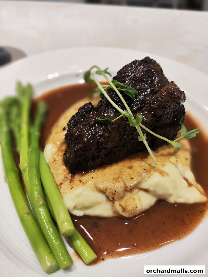 A plate of braised beef short ribs served with mashed potatoes and asparagus.