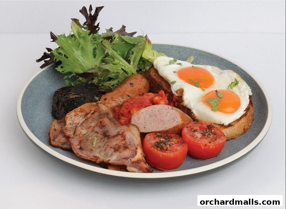 A hearty breakfast plate with eggs, sausages, bacon, beans, and salad.