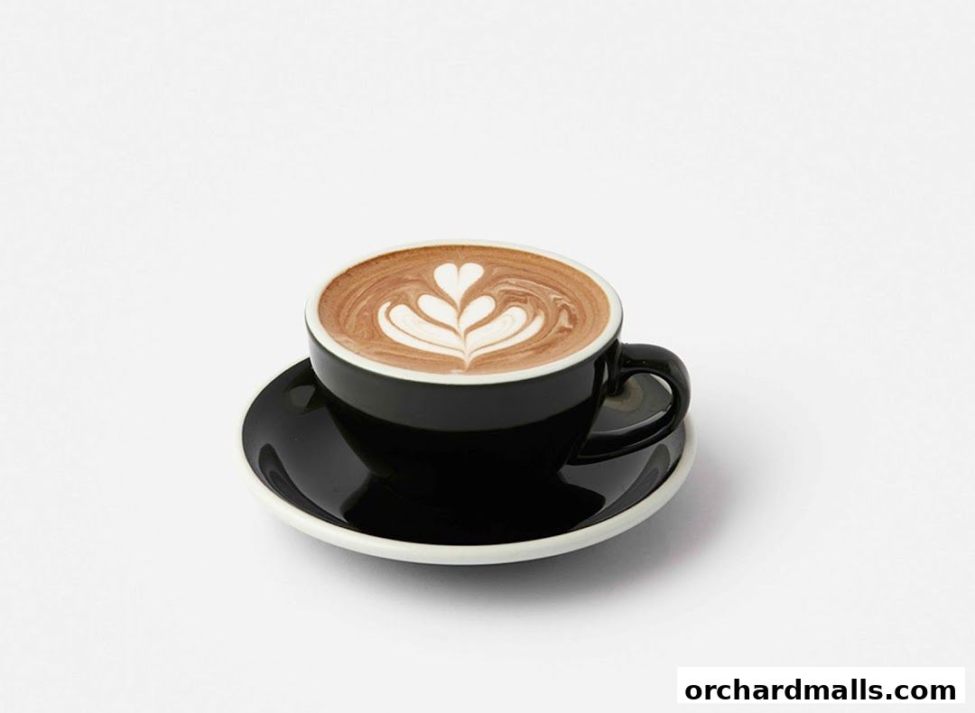 A black cup of coffee with latte art on a white saucer.