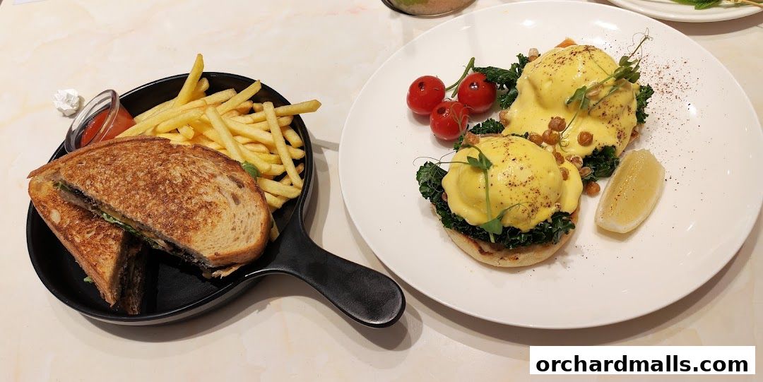 A delicious breakfast spread featuring eggs benedict, a grilled sandwich, and french fries.
