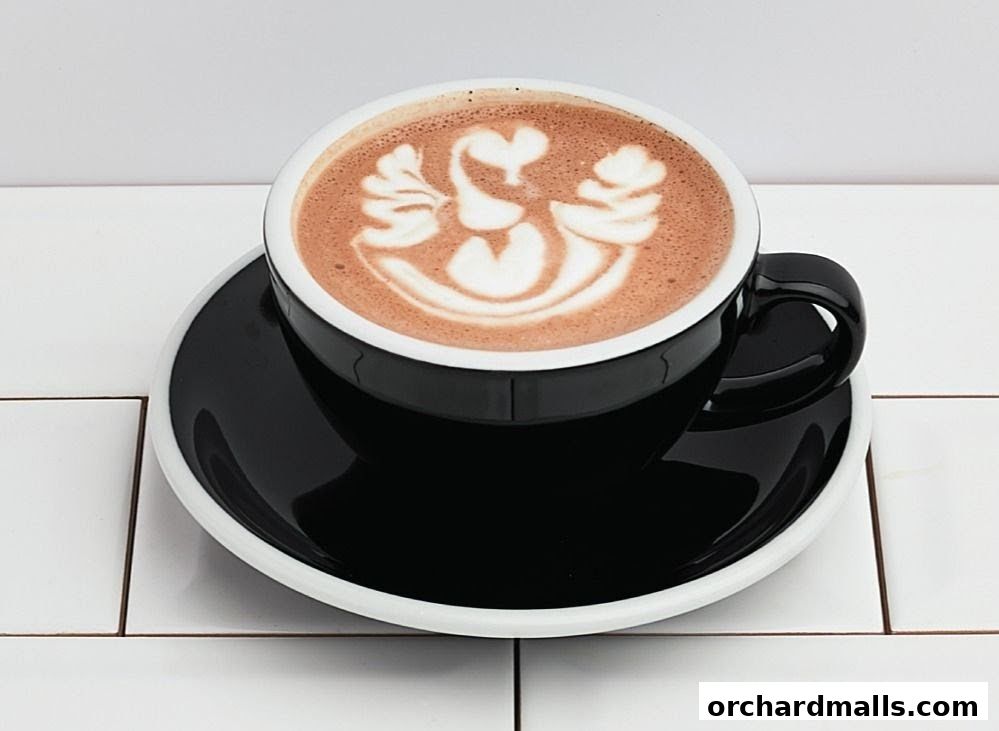 A black cup of hot chocolate with latte art of a swan on a saucer.
